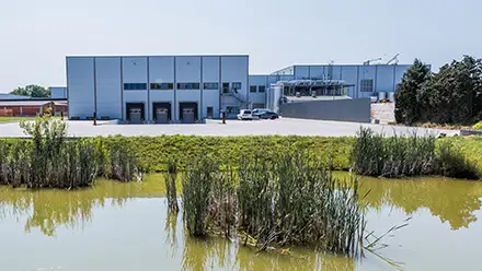 Ansicht Firmengebäude mit Parkplatz hinter einem Teich